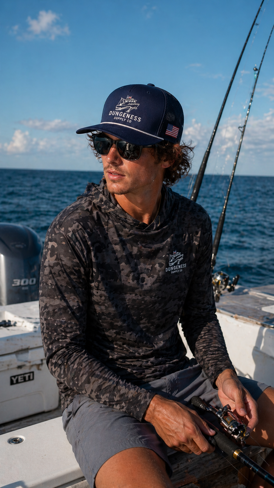Navy trucker cap and charcoal digital camo long-sleeve fishing shirt, worn on a fishing boat at sea
